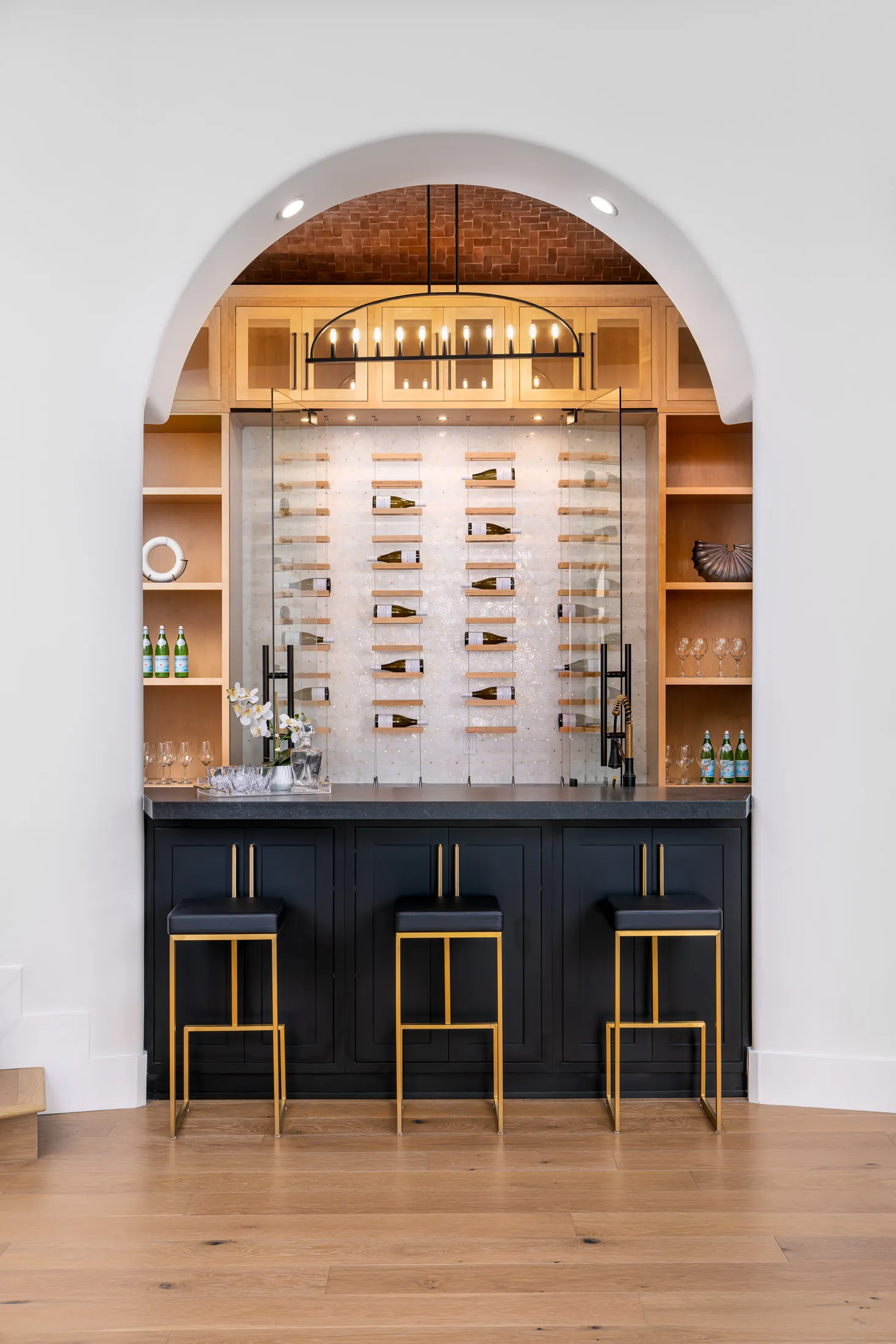Stylish home bar with black countertop, gold bar stools and wine display wall